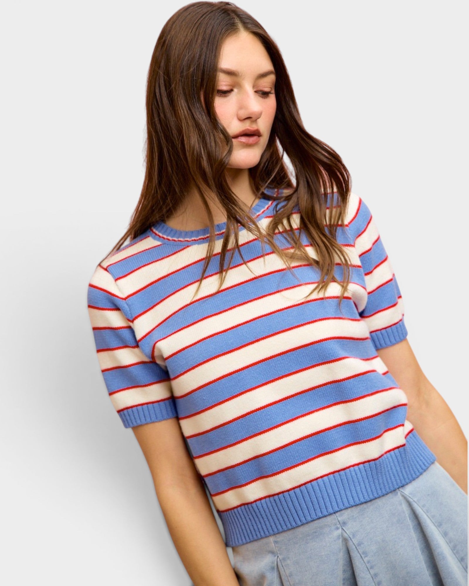 Woman wearing a blue, red, and white striped sweater on a light gray background