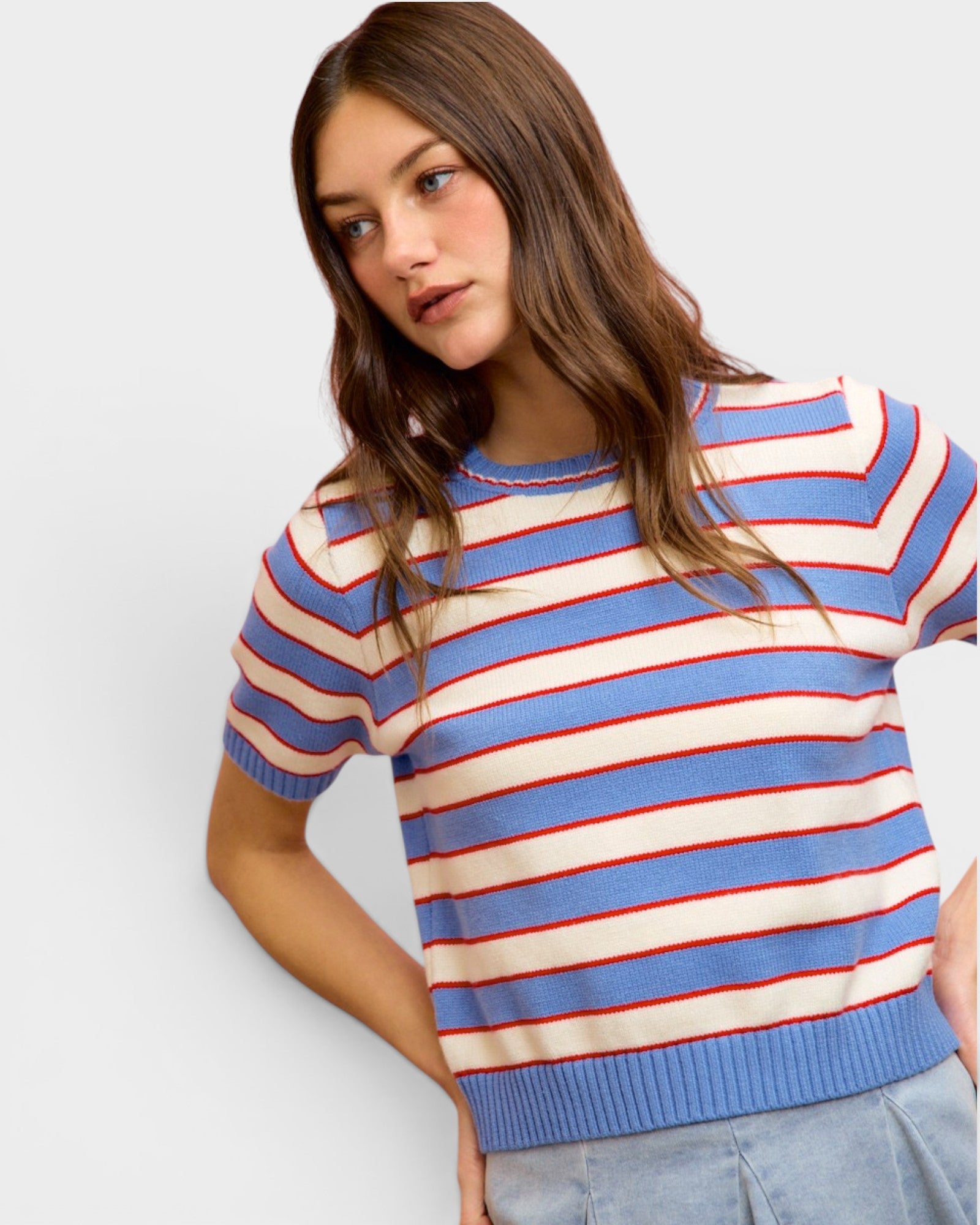 Woman wearing a striped sweater with blue, red, and white colors on a plain background