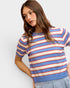 Woman wearing a striped sweater with blue, red, and white colors on a plain background