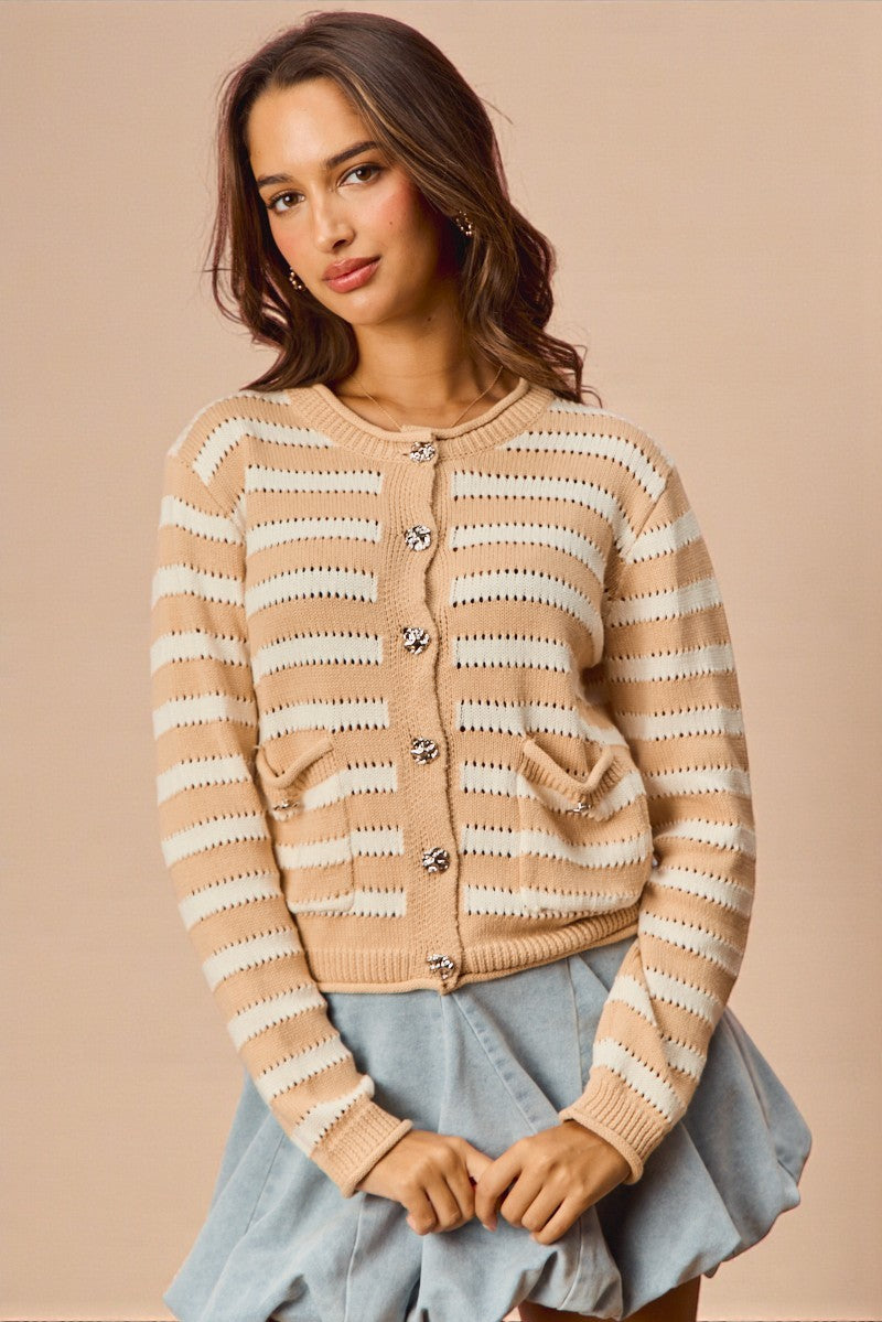 Woman wearing a beige and white striped cardigan against a beige background