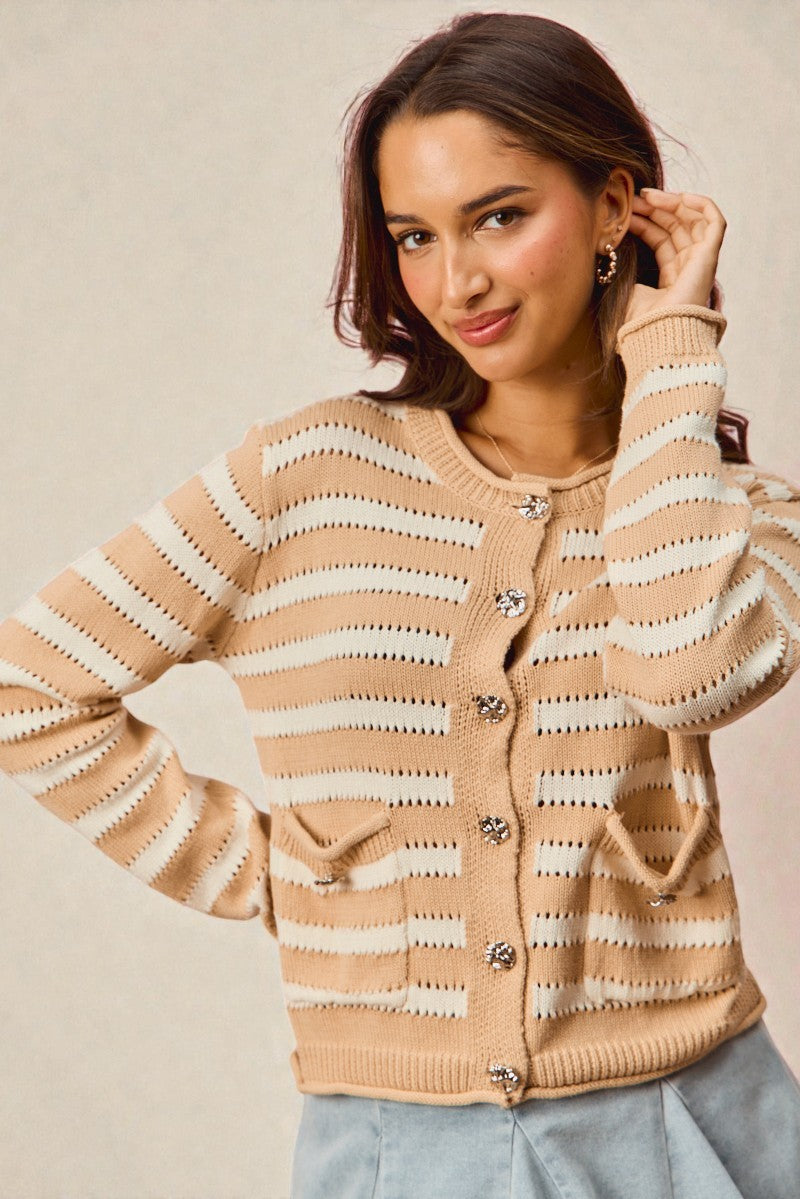 Woman wearing a beige and white striped sweater with ruffled sleeves on a beige background