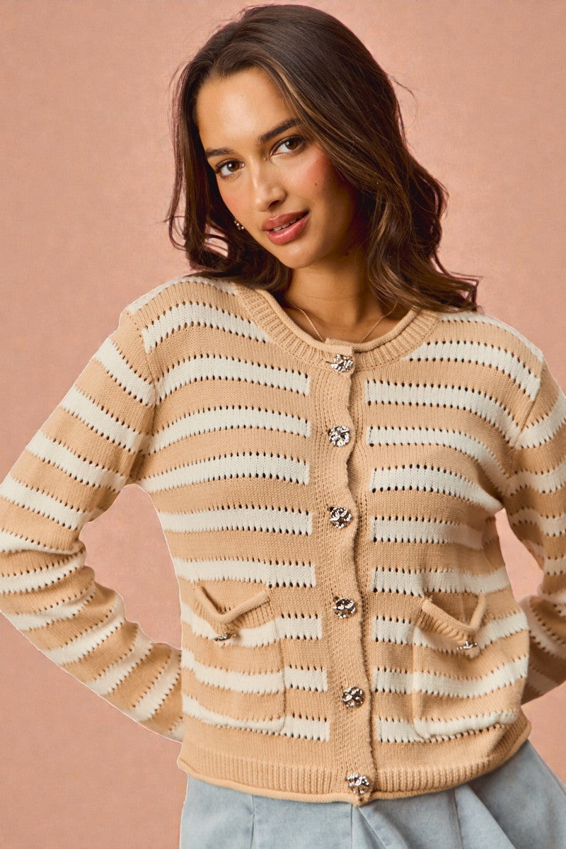 Woman wearing a beige and white striped cardigan on a pink background