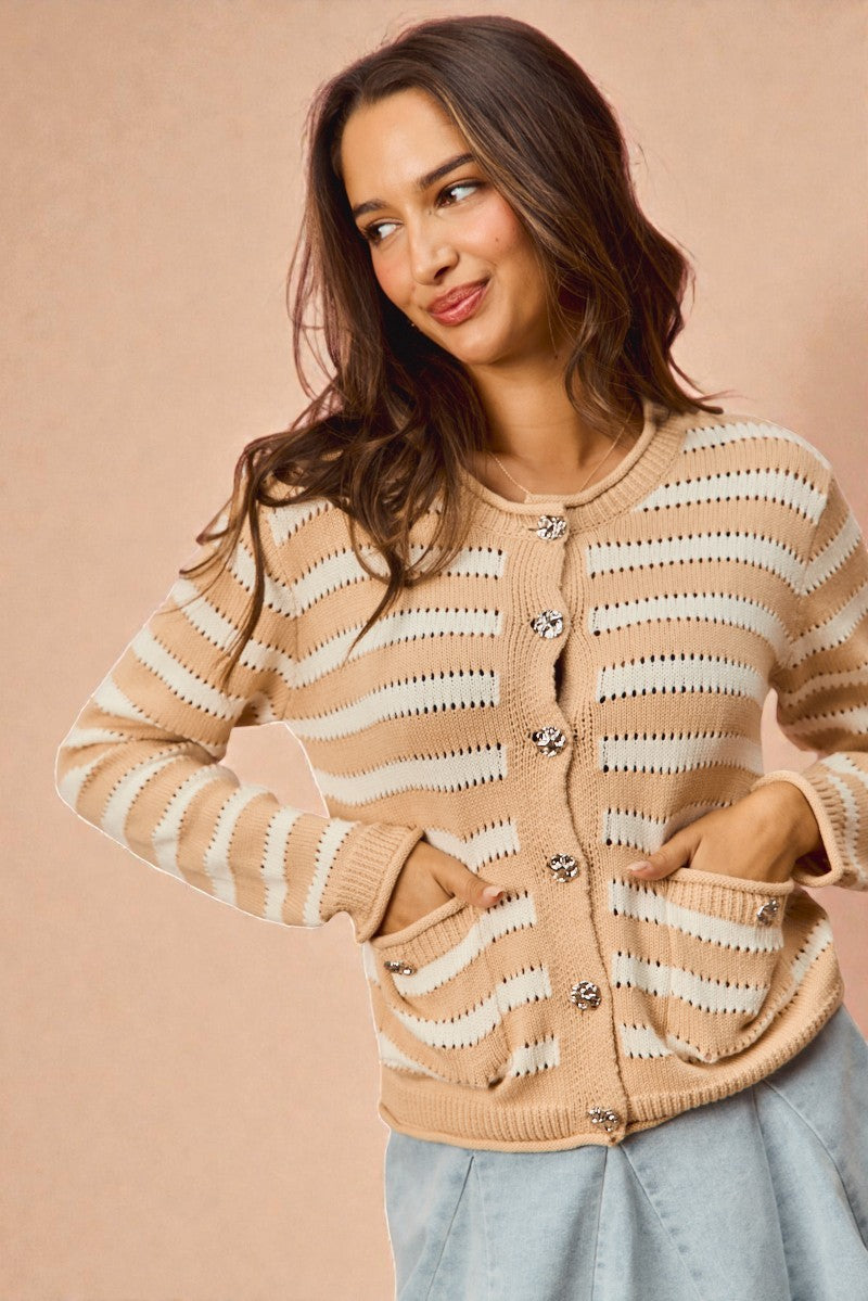 Woman wearing a beige and white striped cardigan against a beige background