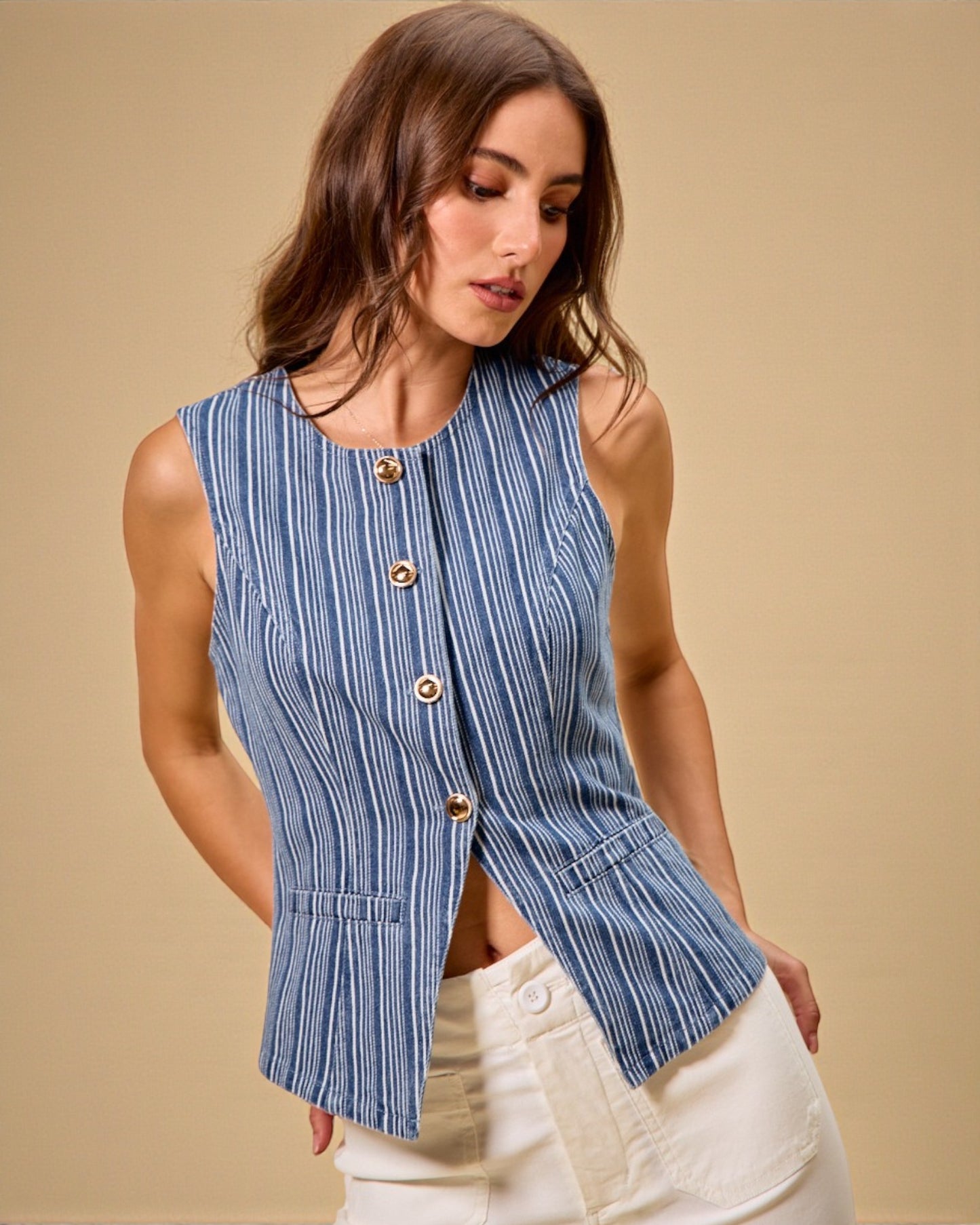 Woman wearing a blue striped sleeveless top against a beige background