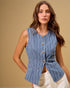 Woman wearing a blue striped sleeveless top with gold buttons against a beige background