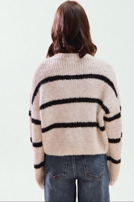 Person wearing a beige and black striped sweater on a light background