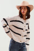Woman wearing a patterned sweater and wide-brimmed hat against a white background