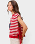 Woman wearing a red and white striped sleeveless top with an American flag design on a plain background