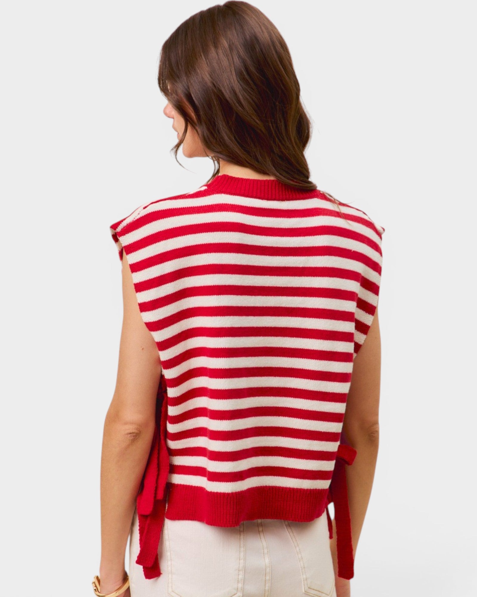 Red and white striped sleeveless sweater worn by a person on a light gray background