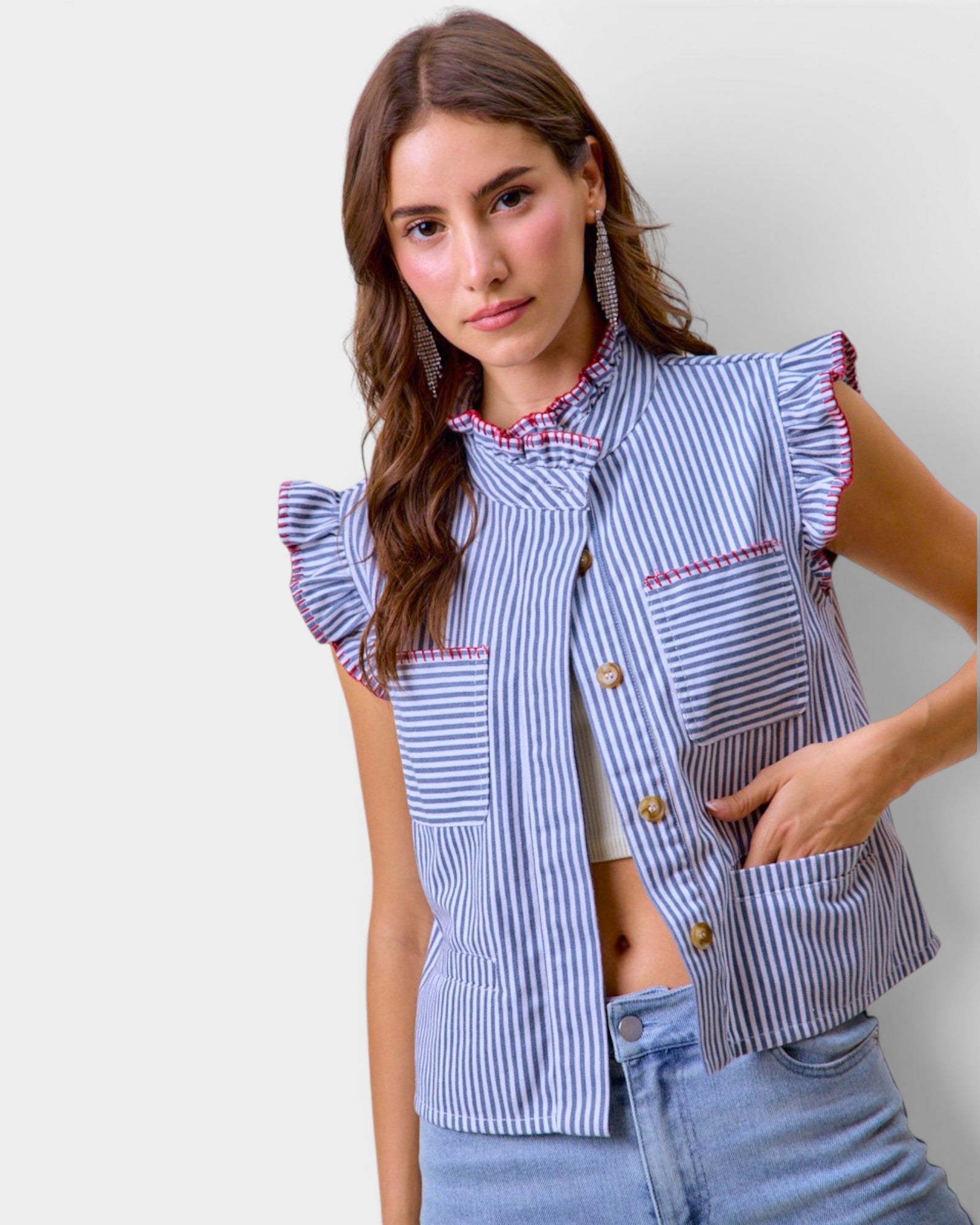Woman wearing a blue and white striped shirt with ruffled sleeves against a plain background
