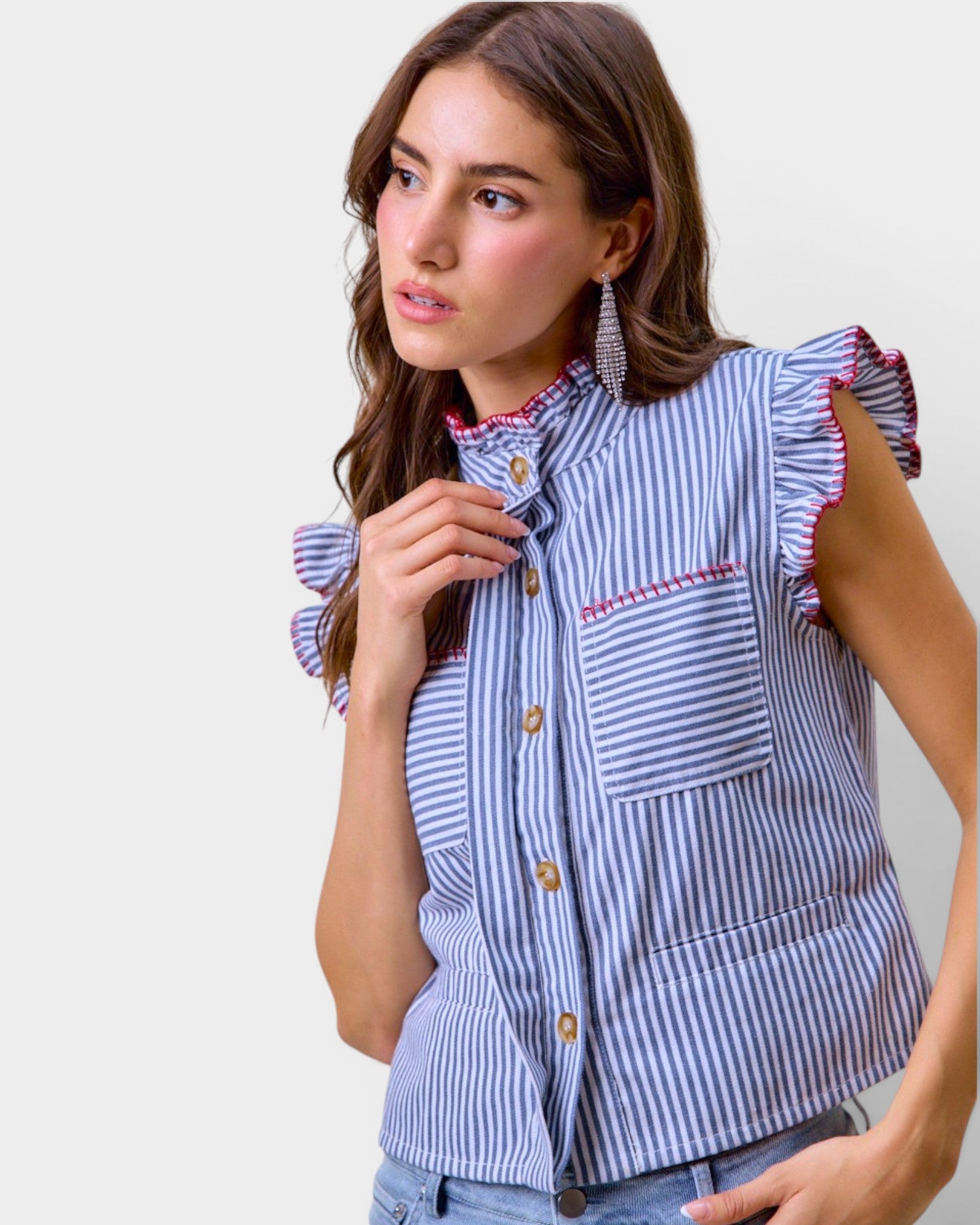 Woman wearing a blue and white striped shirt with ruffled sleeves against a plain background