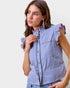 Woman wearing a blue and white striped shirt with ruffled sleeves against a plain background