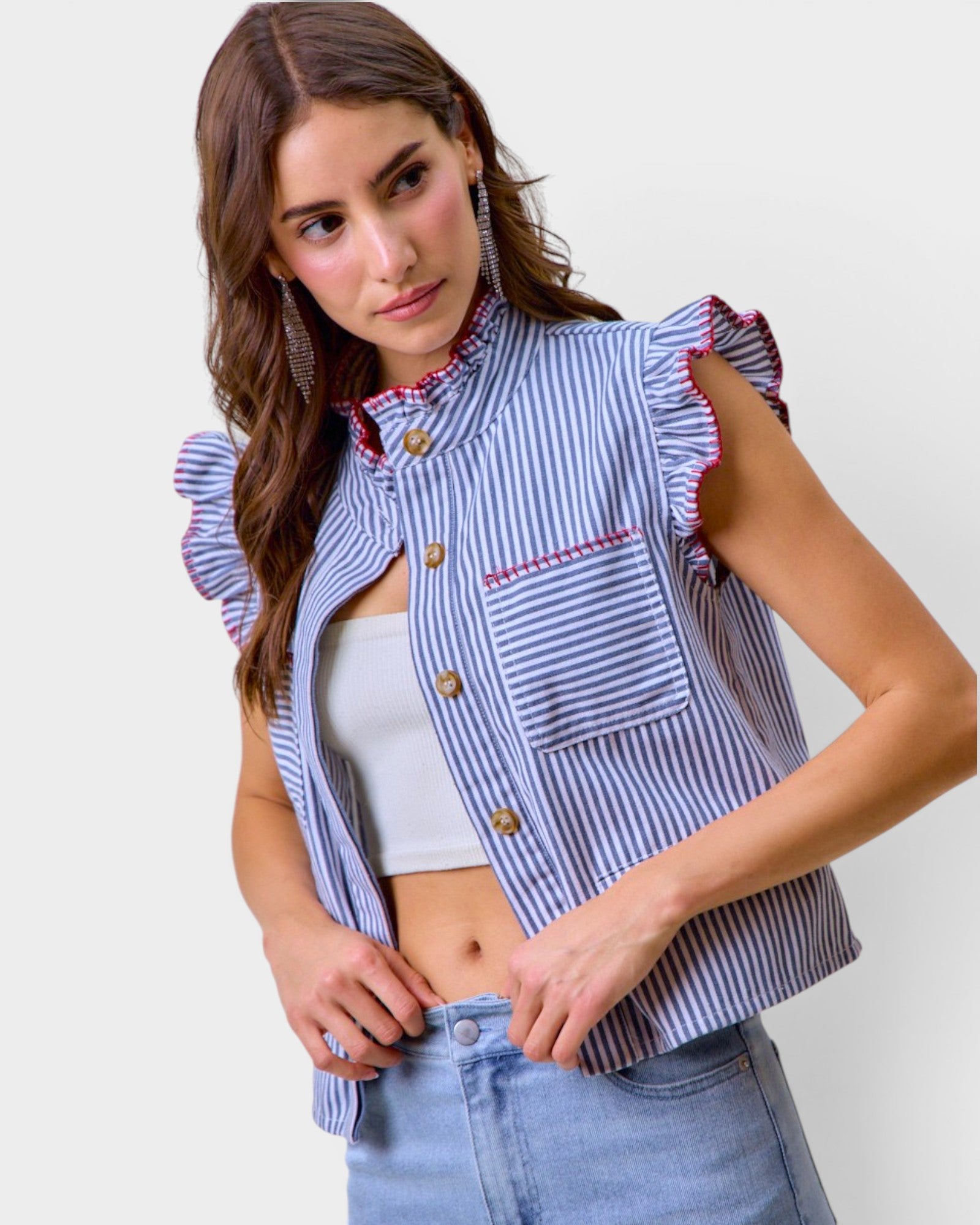 Woman wearing a blue and white striped shirt with ruffled sleeves against a plain background
