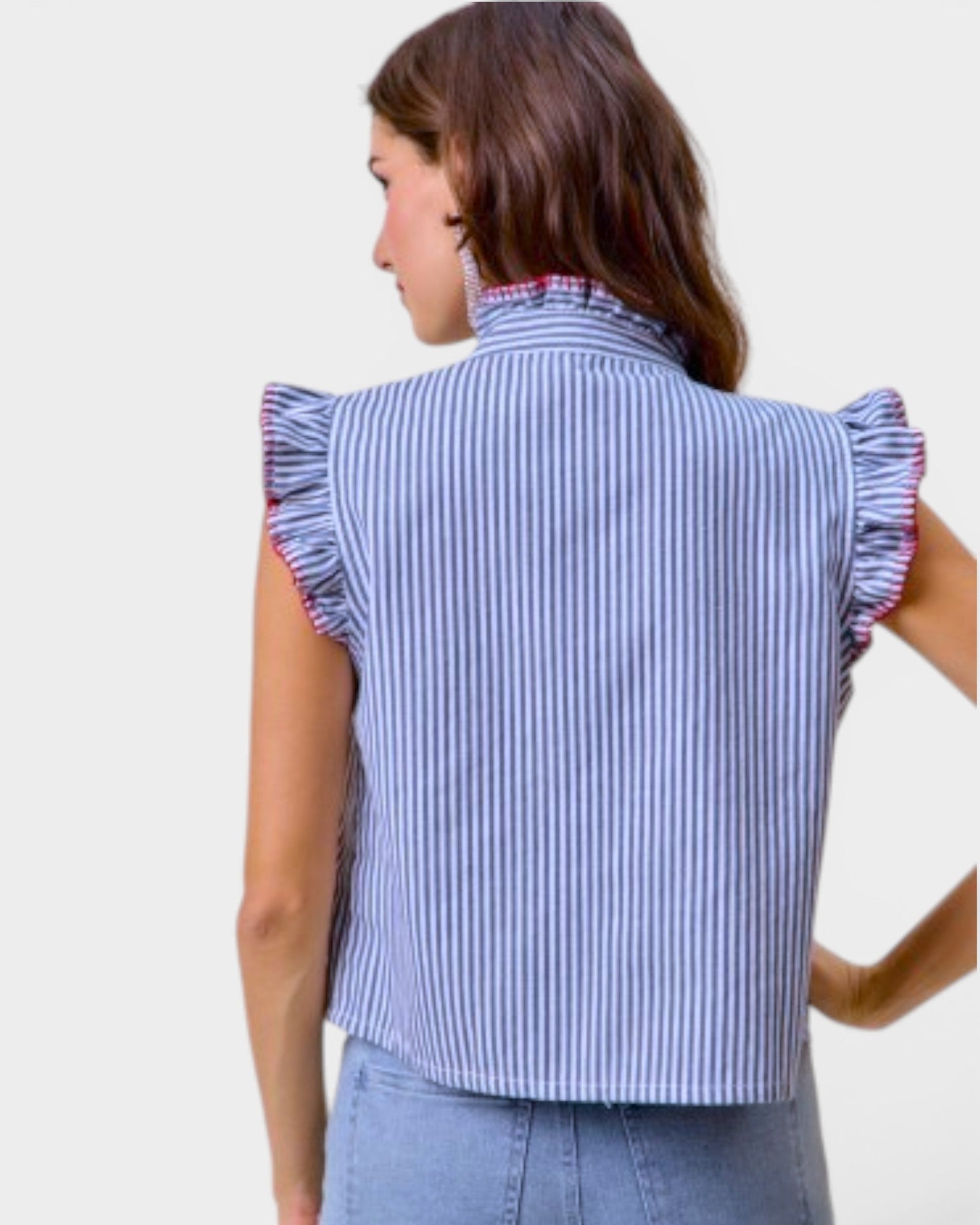Woman wearing a blue and white striped shirt with ruffled sleeves against a plain background