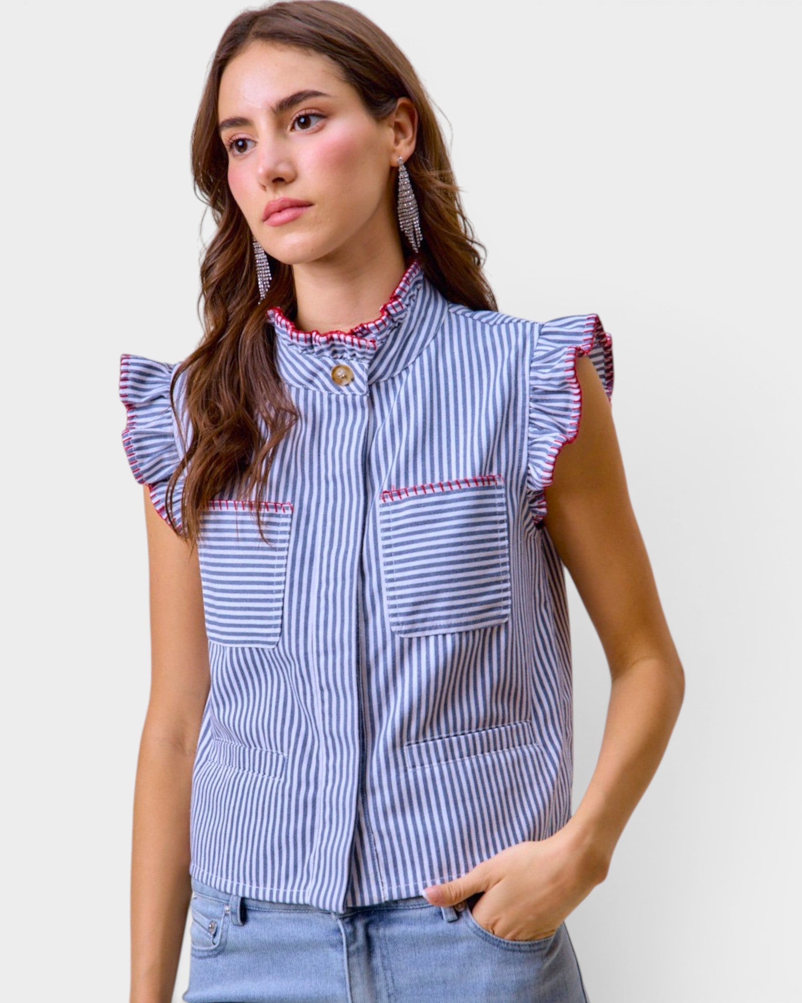 Woman wearing a blue and white striped shirt with ruffled sleeves against a plain background