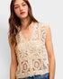Woman wearing a beige crochet vest against a white background