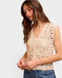 Woman wearing a beige lace top with a plain background