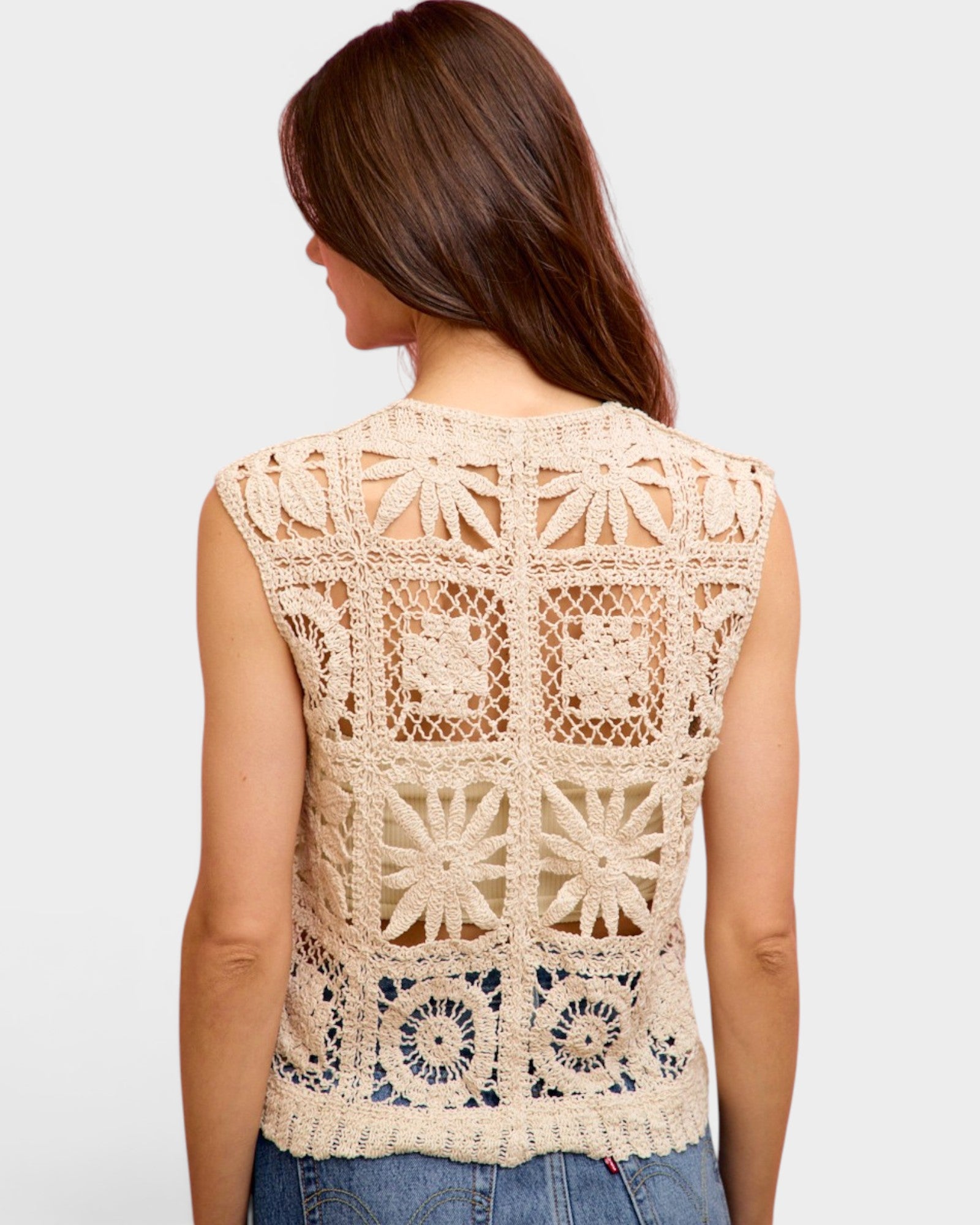 Woman wearing a beige crochet sleeveless top on a white background