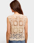 Woman wearing a beige crochet sleeveless top on a white background