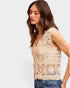 Woman wearing a beige crochet top against a plain background