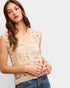 Woman wearing a beige lace top against a plain background