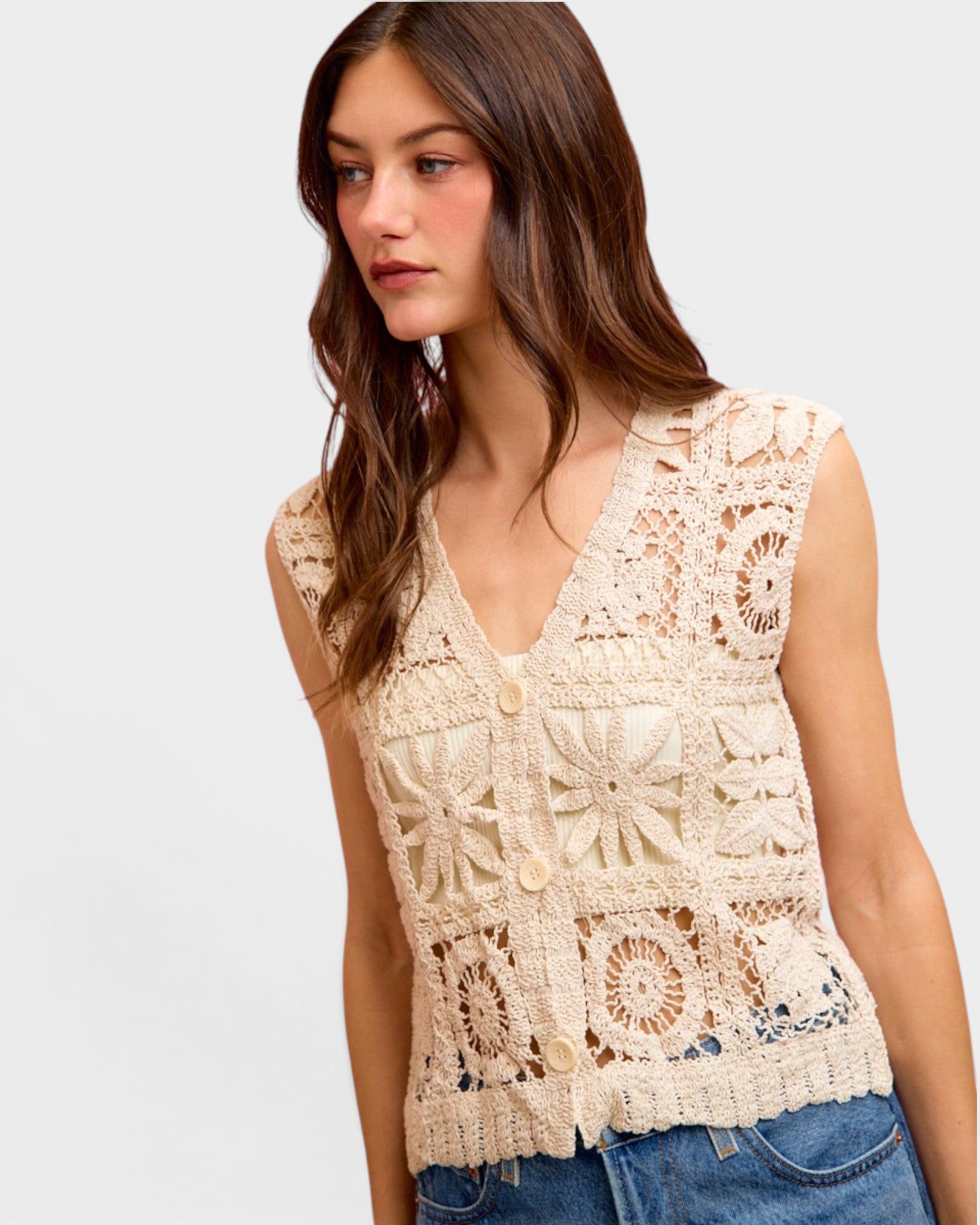 Woman wearing a beige crochet top against a plain background