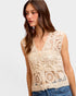 Woman wearing a beige crochet top against a plain background