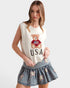Woman wearing a sleeveless top with a teddy bear and 'USA' text and a denim skirt with star patterns.