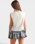 Person wearing a white sleeveless sweater and denim skirt with star patterns on a plain background