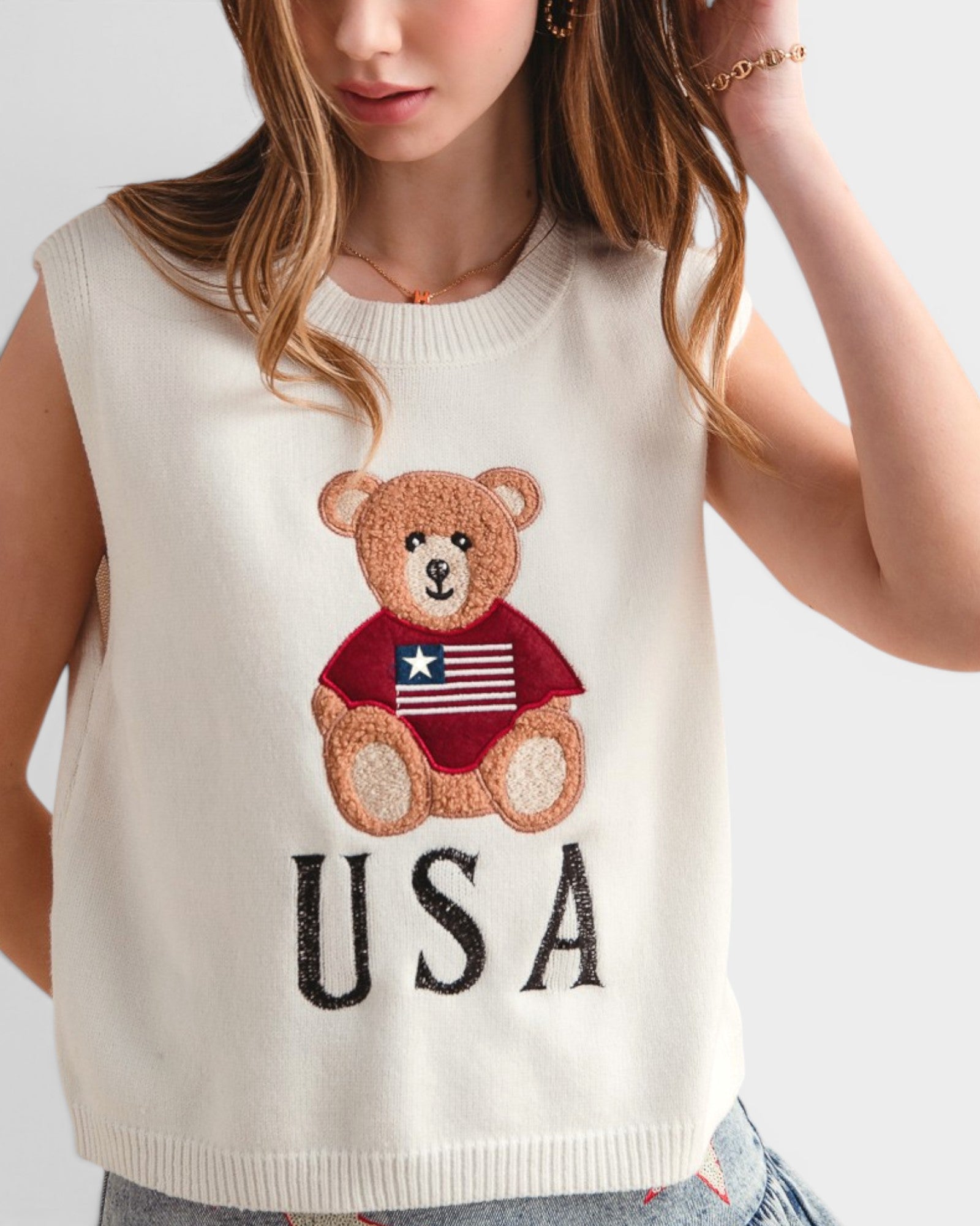 White sleeveless top with teddy bear and 'USA' text design worn by a person.
