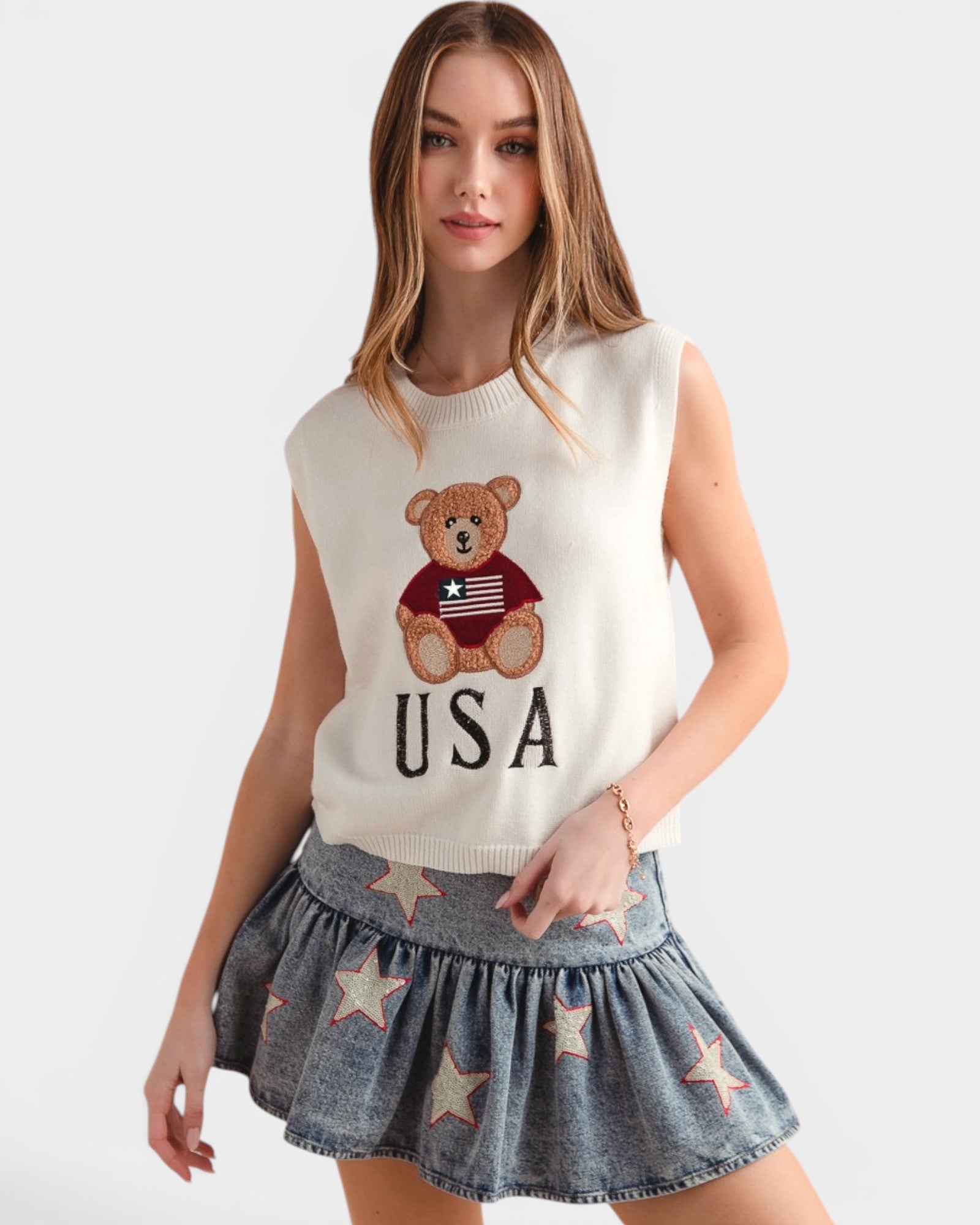 Woman wearing a sleeveless top with a bear graphic and 'USA' text, paired with a denim skirt.