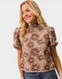 Woman wearing a floral patterned blouse with puff sleeves on a white background