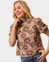 Woman wearing a floral patterned top with a plain background