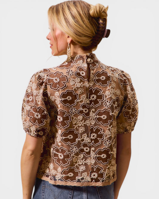 Woman wearing a brown floral blouse against a white background