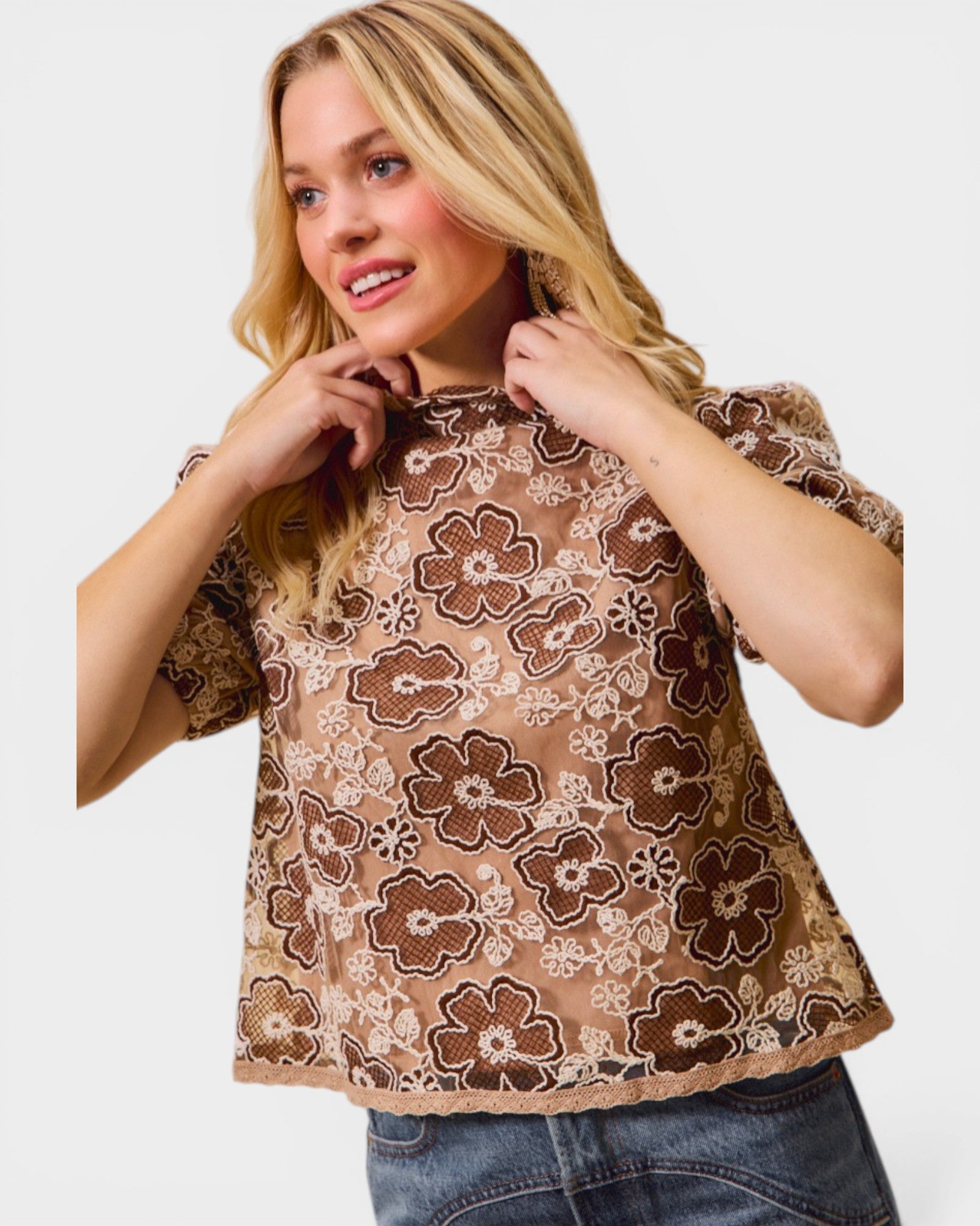 Woman wearing a brown floral top against a white background
