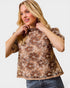 Woman wearing a brown floral top against a white background