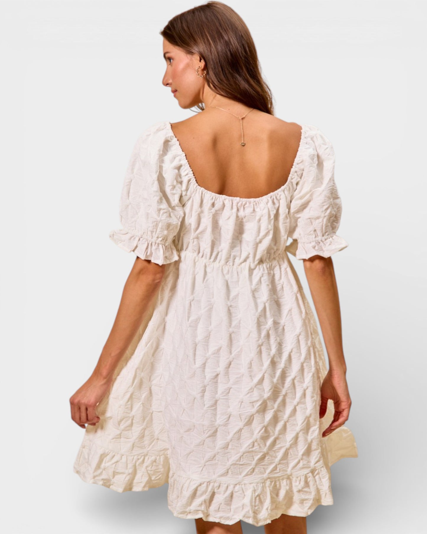 Woman wearing a white dress with a plain background