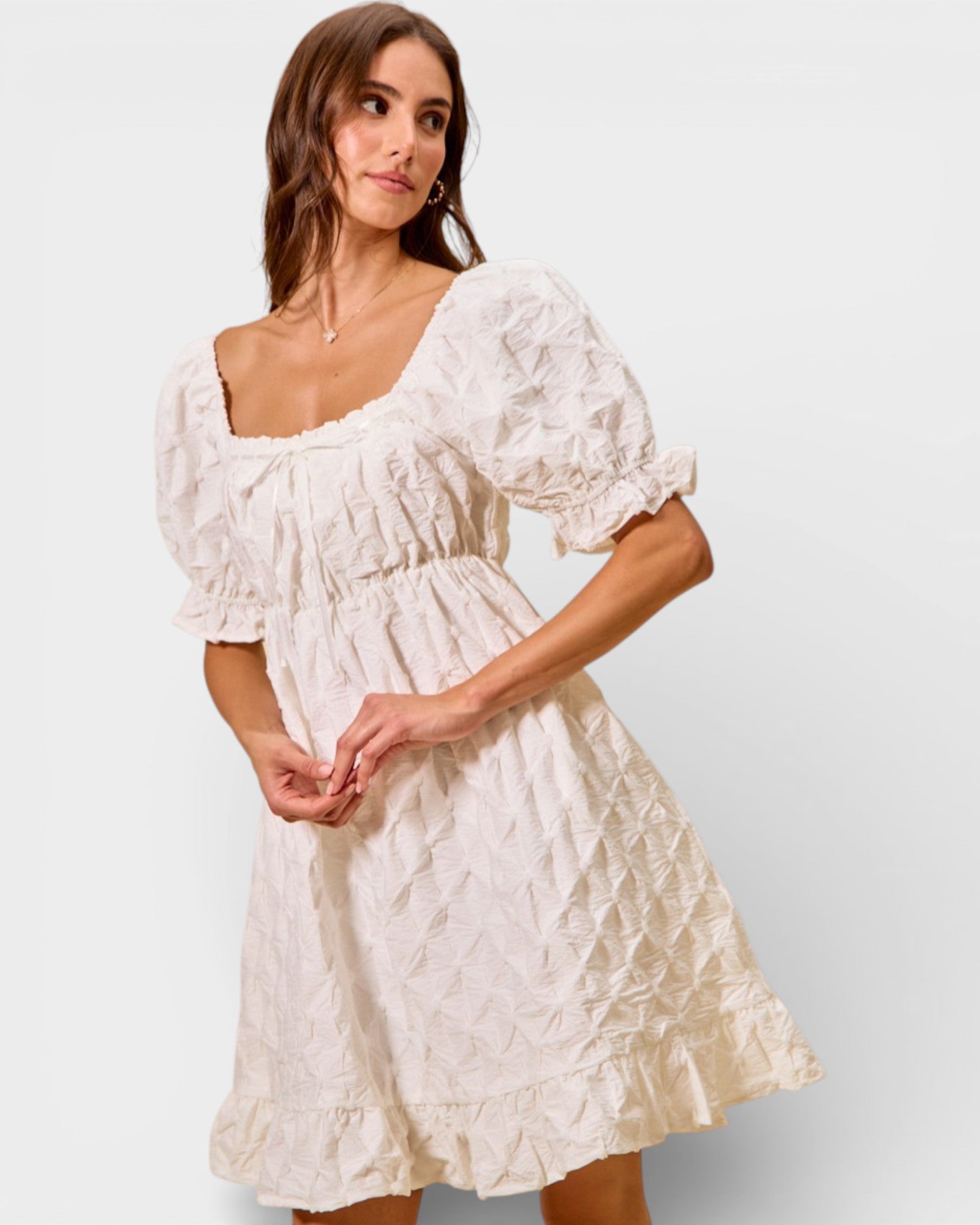 Woman wearing a white lace dress against a plain background