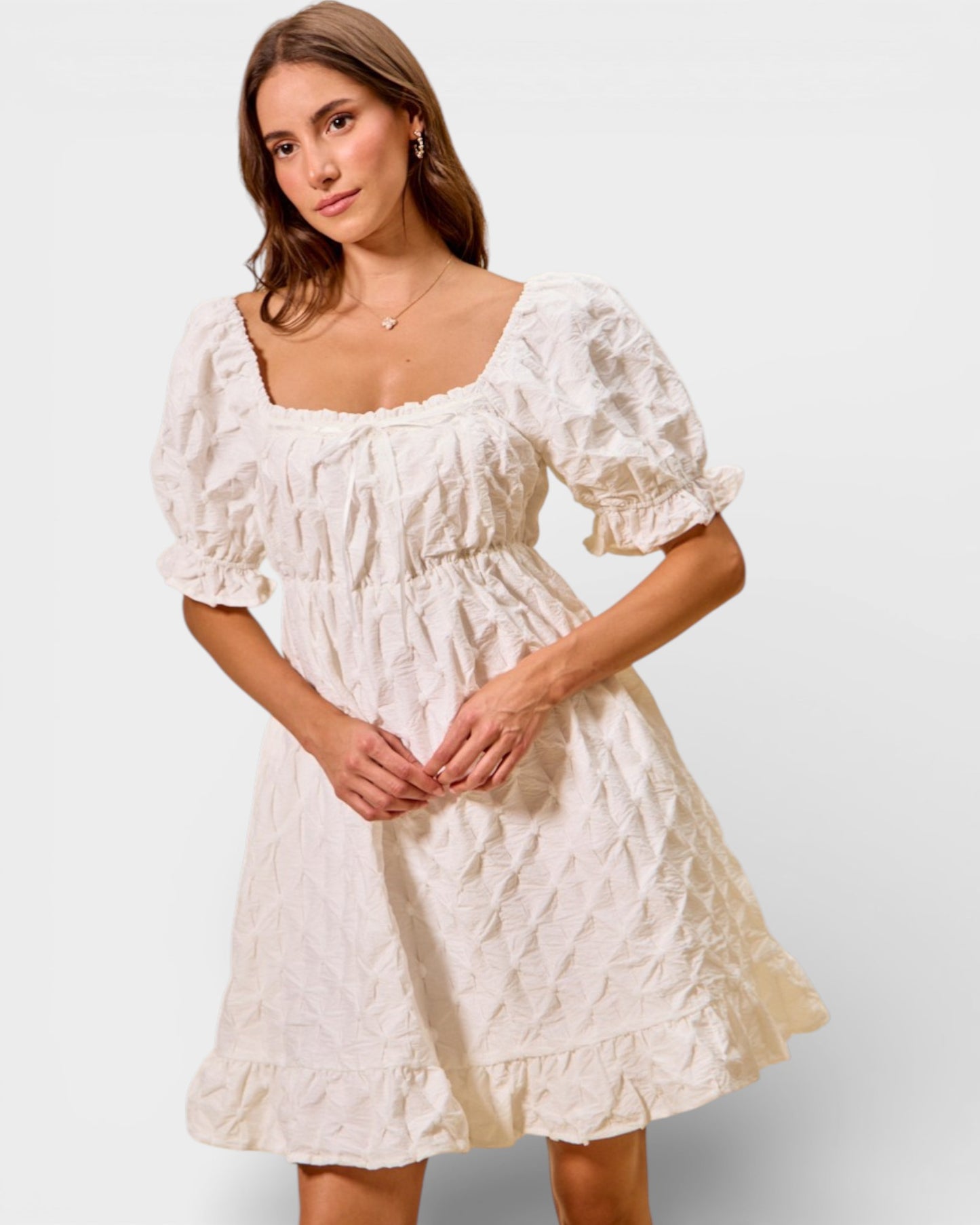 Woman wearing a white lace dress against a plain background