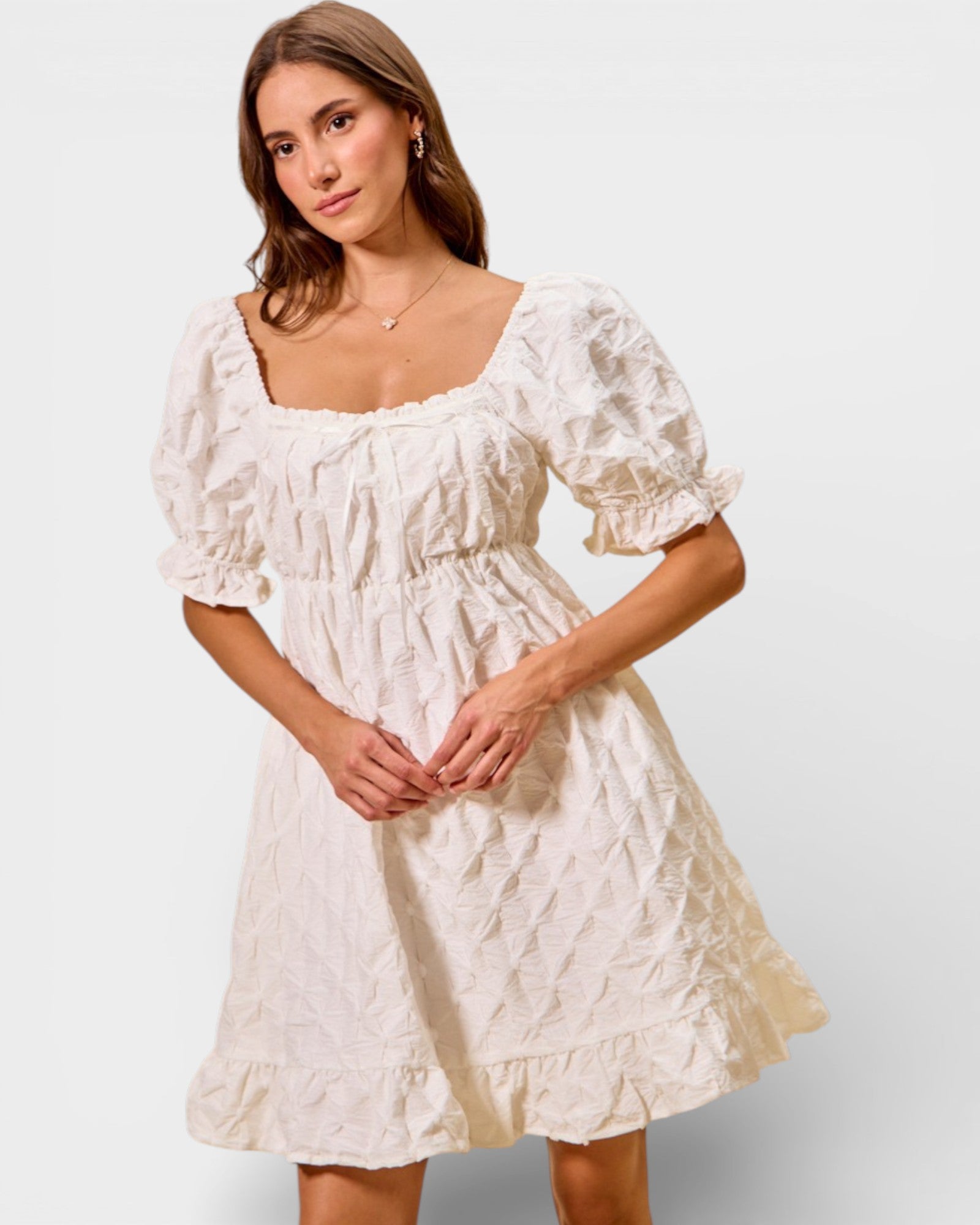 Woman wearing a white lace dress against a plain background