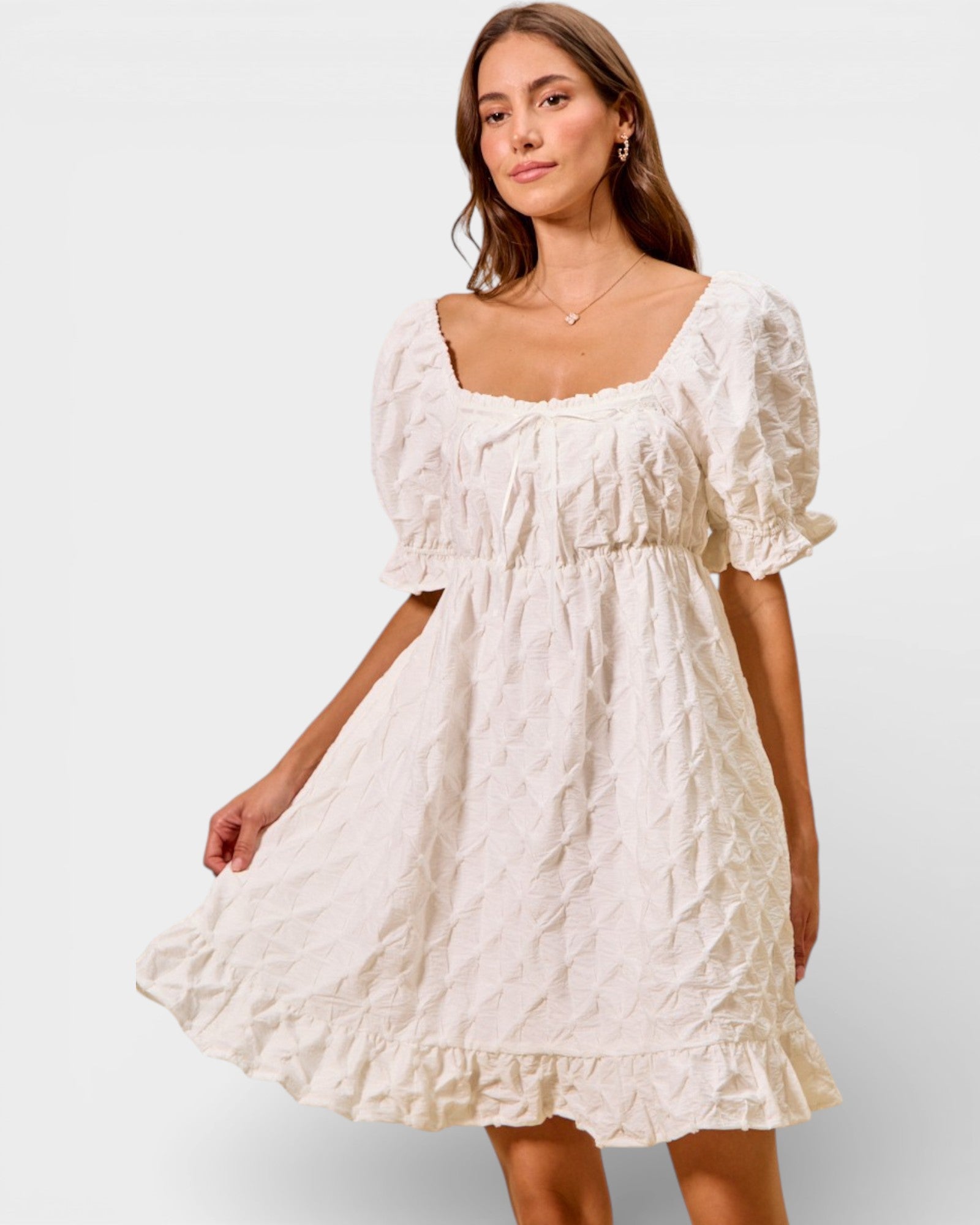 Woman wearing a white lace dress against a plain background