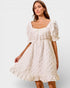 Woman wearing a white lace dress against a plain background