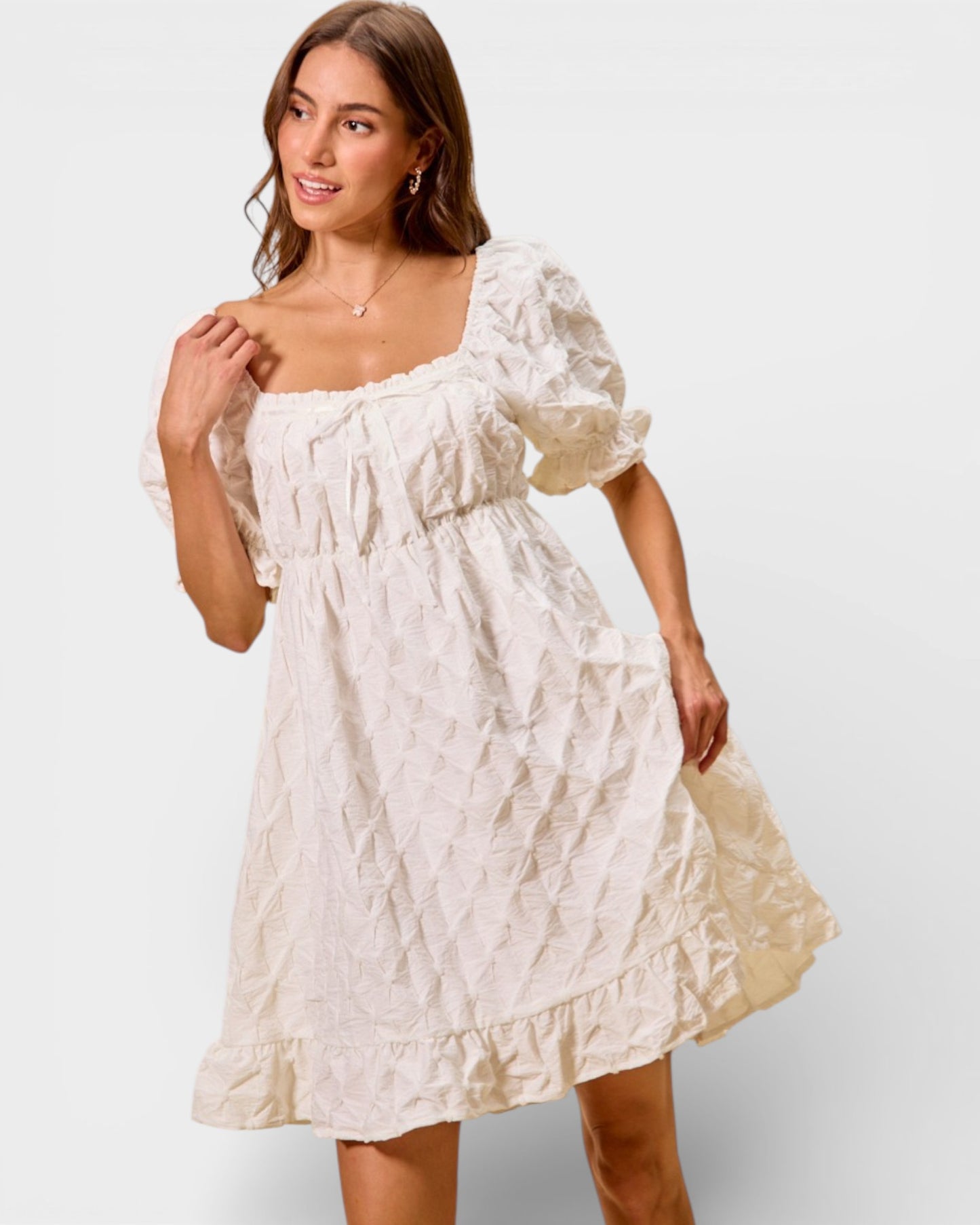 Woman wearing a white dress with puffed sleeves on a plain background