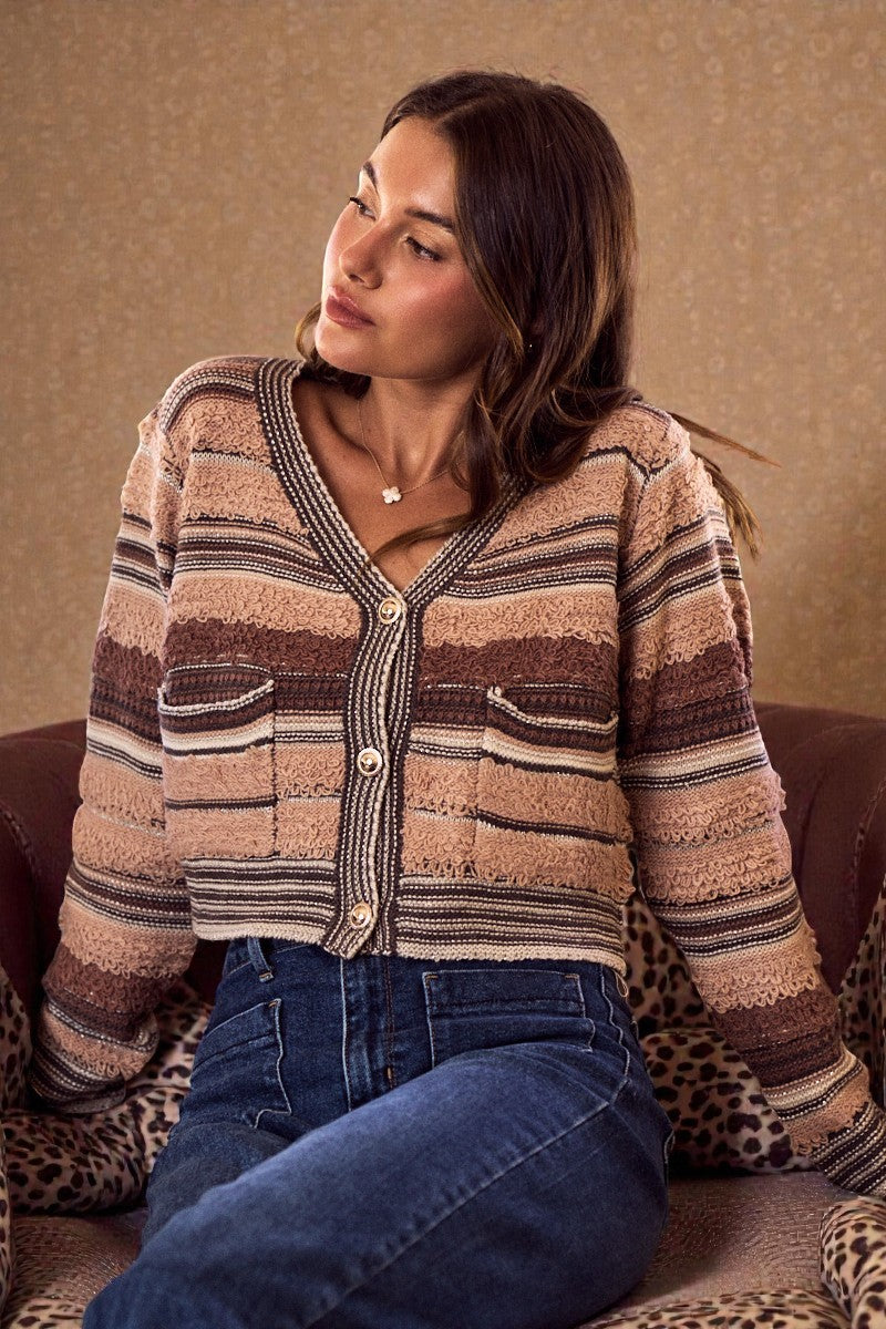Woman wearing a striped cardigan sitting on a patterned chair.
