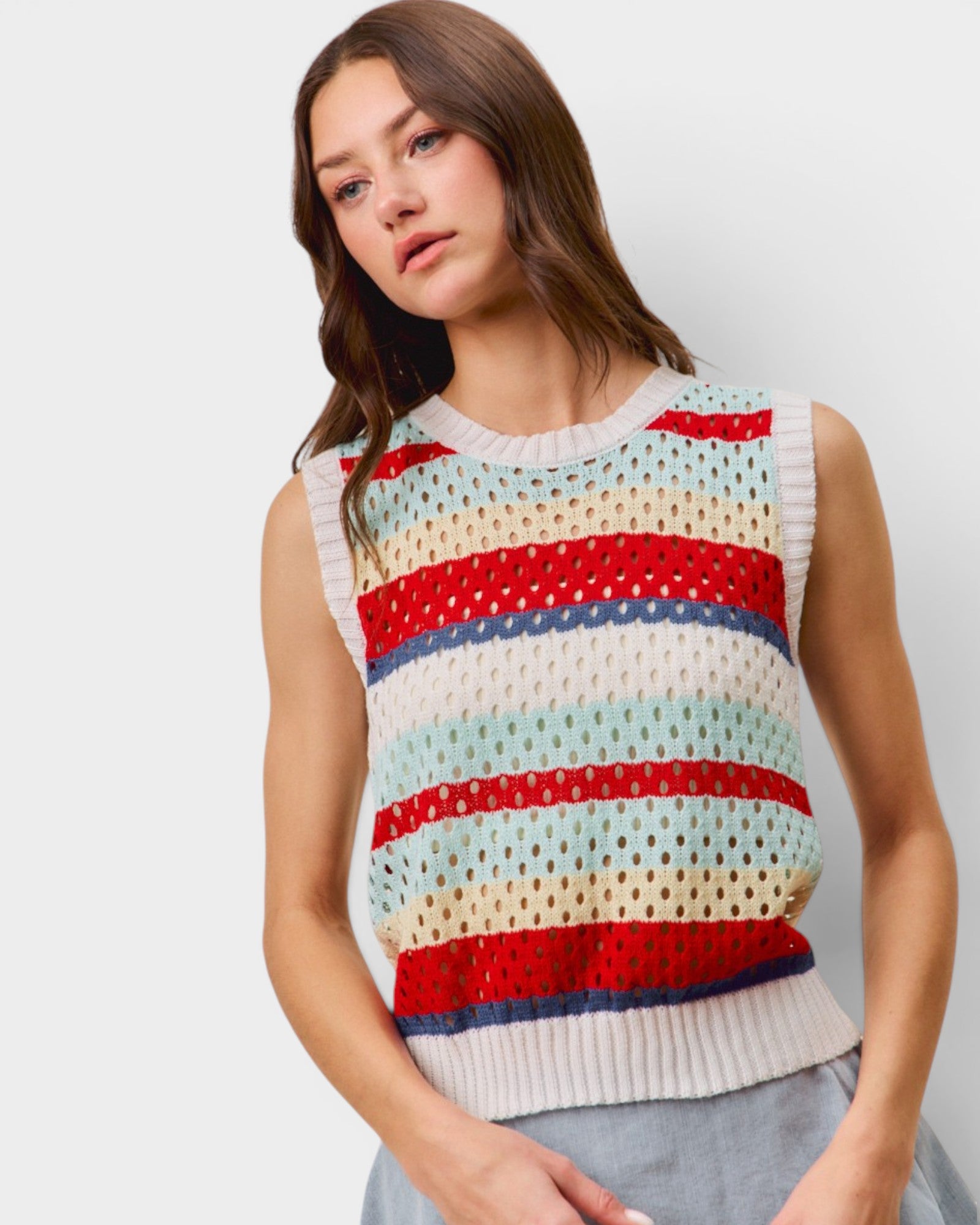 Woman wearing a colorful striped sleeveless sweater against a plain background