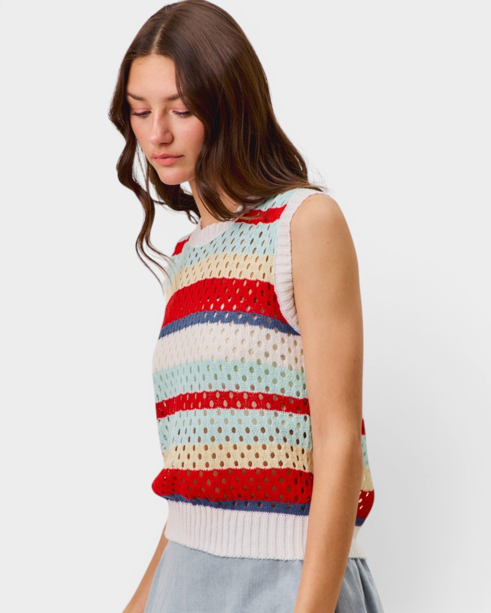 Woman wearing a colorful striped sleeveless sweater against a plain background