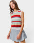 Woman wearing a colorful striped sleeveless top and denim skirt on a white background
