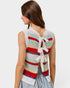 Woman wearing a colorful striped sleeveless top with a white lace detail on a light gray background