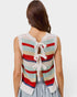 Woman wearing a colorful crochet vest with a white lace bow on a light gray background