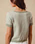 Woman wearing a green and white patterned short-sleeve sweater against a beige background